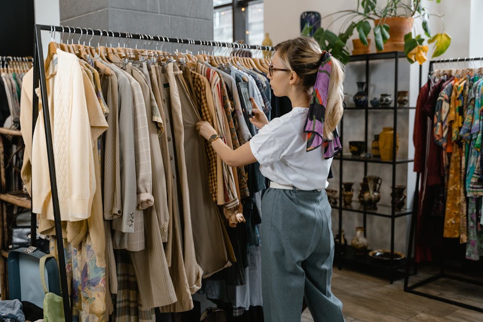 Woman browsing through clothes on hangers in a stylish boutique setting.